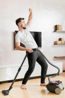 Man dancing with vacuum cleaner long shot