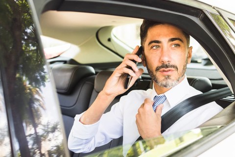 Modern man sitting car adjusting his neck tie talking mobile phone