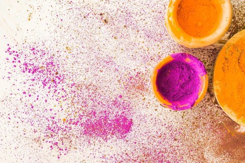 Pink yellow holi powder bowl with stained white background