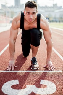 Portrait confident male athlete starting line race track
