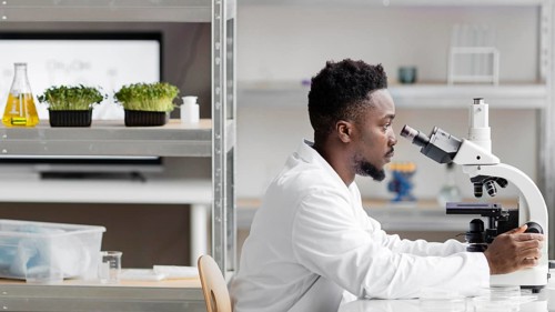 Side view male researcher laboratory looking through microscope