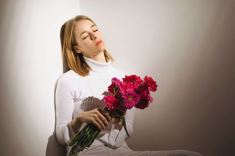 Thoughtful woman sitting with pink flowers bouquet