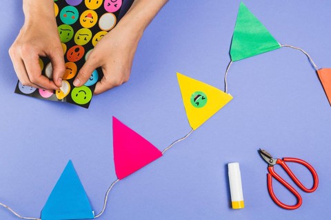 Woman hand making bunting with emoji stickers colored background