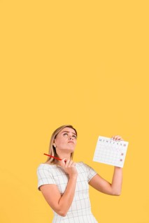 Woman looking up holding menstruation calendar with copy space