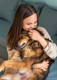 Woman petting her cute dog home during pandemic