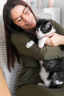 Woman playing with cat sitting chair
