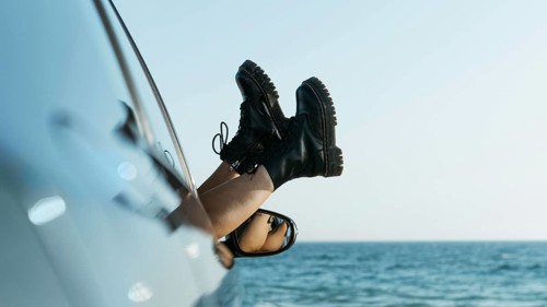 Woman s feet out car window near sea
