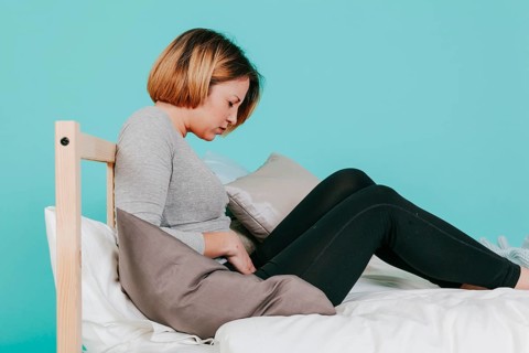 Woman touching hurting belly bed