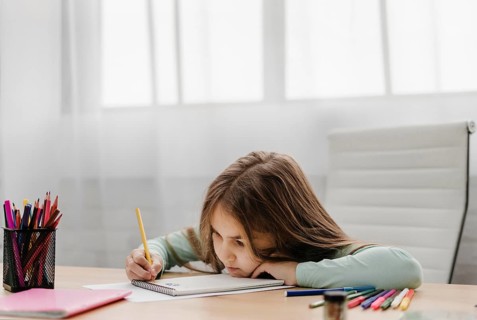 Bored little girl taking notes