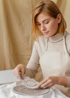 Close up woman decorating clay plate