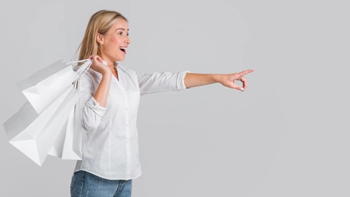 Happy woman holding shopping bags pointing possible store sale