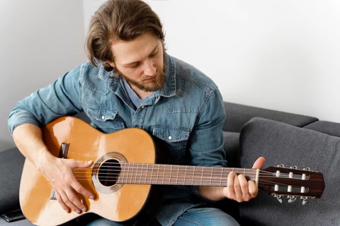Medium shot man playing guitar couch