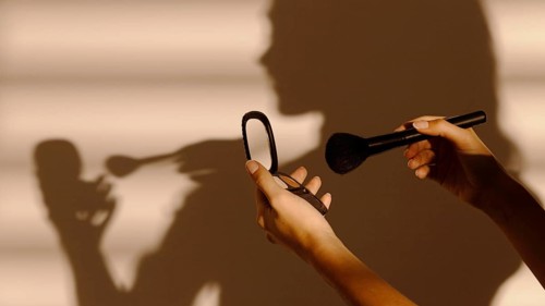 Shadow woman using different cosmetics