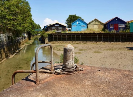Colourful houses and a jetty with bollards at low tide in Le Chateau-d'Oleron