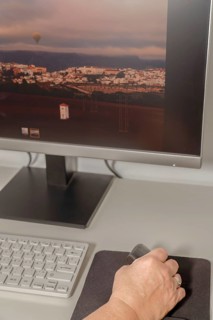 Woman's hand working at her computer with an ergonomic vertical computer mouse to avoid hand pains