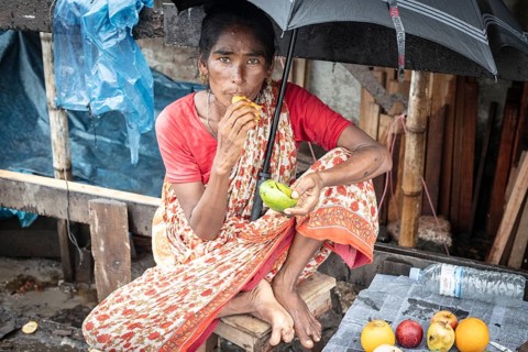 Woman eating a mango in front of her house