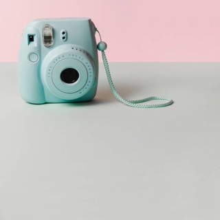 Mini blue instant camera gray desk against pink background