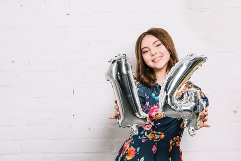 Smiling portrait girl showing numeral 14 foil balloon
