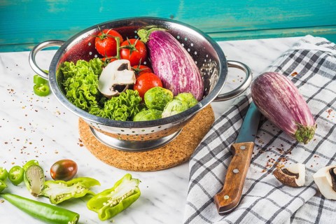 Various fresh vegetables colander marble surface
