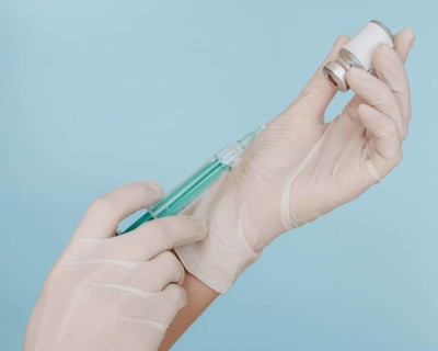 Hands with gloves holding syringe with vaccine bottle