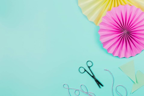 Pink yellow paper fans with scissor thread teal background