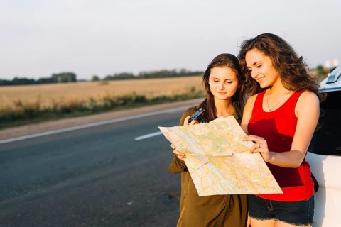 Women standing near white car looking map