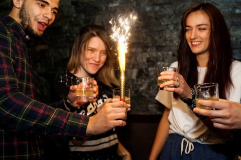 Young man holding lighted sparkle celebrating with friends