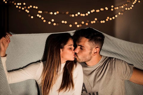 Young woman kissing with man coverlet
