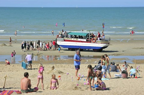 Sunbathers in summer sunbathing and amphibious excursion vehicle on beach along the North Sea coast at Koksijde