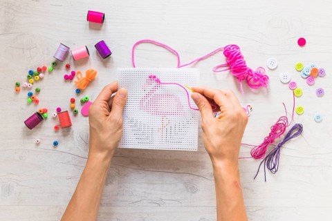 Person hand s doing embroidery with decorative elements textured backdrop