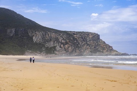 Tourists walking on Nature's Valley sandy beach in the Tsitsikamma Section of the Garden Route National Park