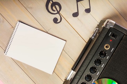 Overhead view spiral notepad musical note amplifier wooden desk