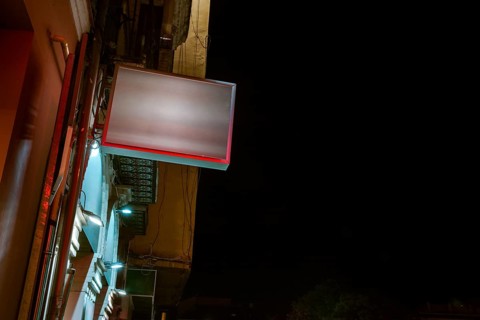 Low angle view illuminated billboard residential building against sky