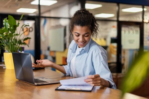 Smiley woman working office with papers laptop