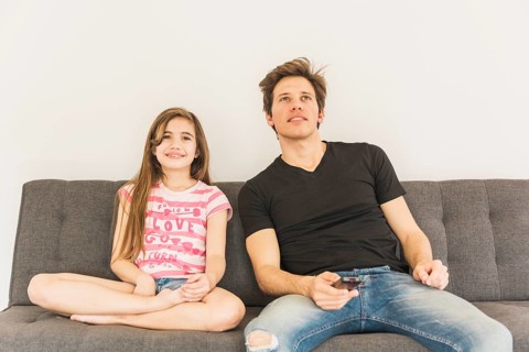 Smiling girl sitting sofa with her father