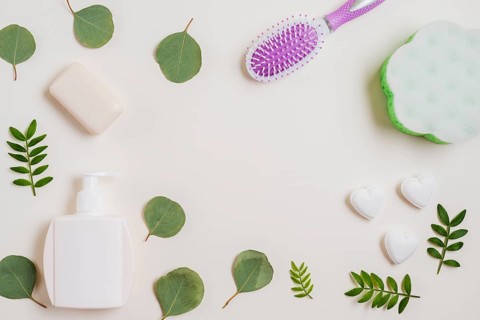 Soap hairbrush dispenser bottle green leaves white backdrop