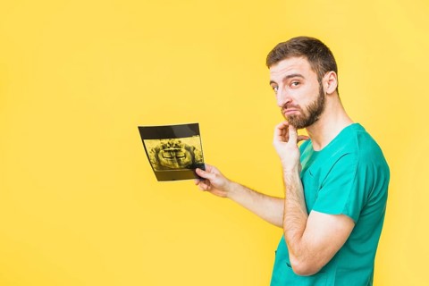 Thoughtful dentist holding teeth x ray