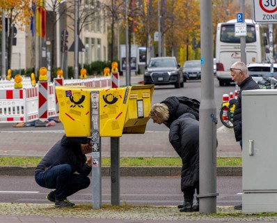 Tourists marvelling at and examining a yellow letterbox by the roadside