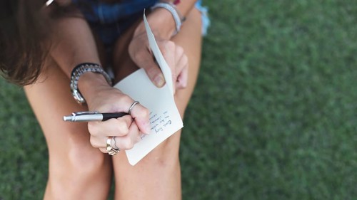 Young woman writing message paper with pen