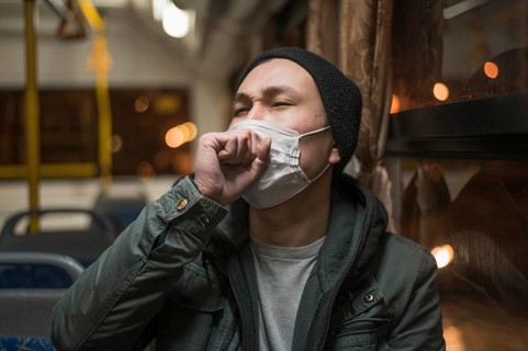 Front view sick man coughing bus while wearing medical mask