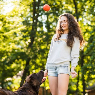 Young woman throwing ball her dog park