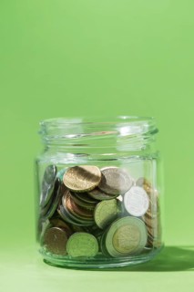 Close up coins inside glass container green background