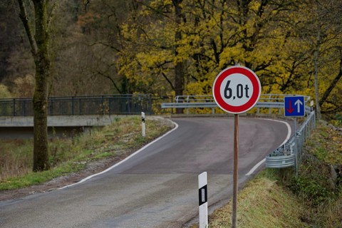 Signs with traffic regulations for weight restriction and right of way on bridge with narrow road width