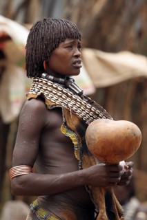 Portrait of woman of the Hamar tribe with calabash in traditional dress