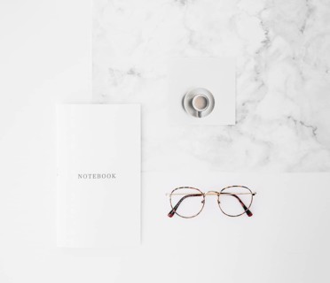 Notebook text paper coffee cup eyeglasses white texture backdrop