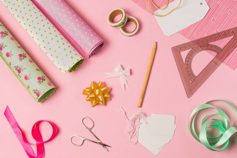 High angle view stationery supplies with gift wrap tags pink background