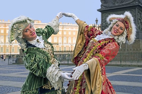 Two Russian women in 18th century period dresses posing for tourists by the Hermitage Winter Palace on Palace Square in the city St Petersburg