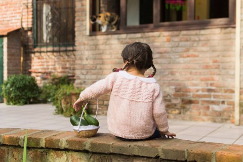 Rear view girl sitting wall holding avocado fruit small basket