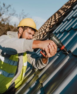 Side view man working roof with drill