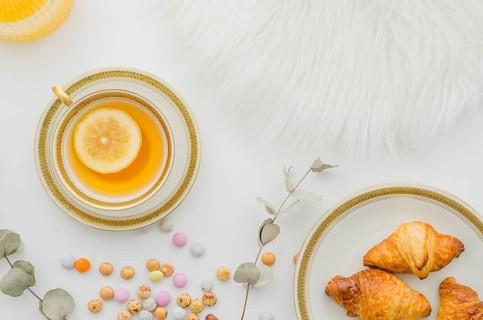 Fur baked croissant candies ginger lemon tea cup white background